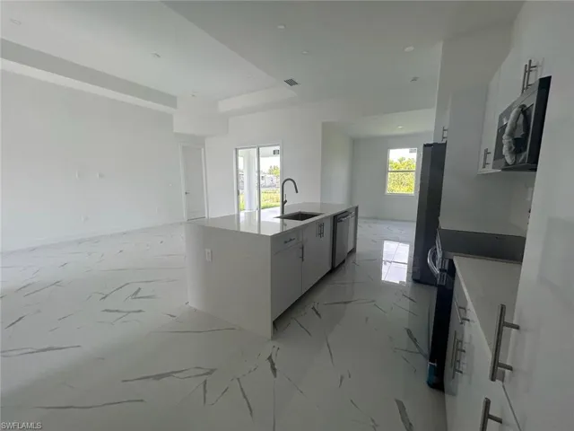 Kitchen featuring a healthy amount of sunlight, appliances with stainless steel finishes, sink, and light tile flooring