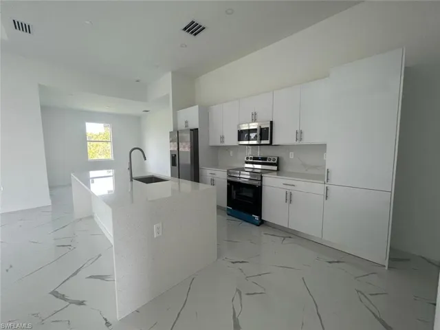 Kitchen featuring tasteful backsplash, stainless steel appliances, a center island with sink, light tile floors, and sink