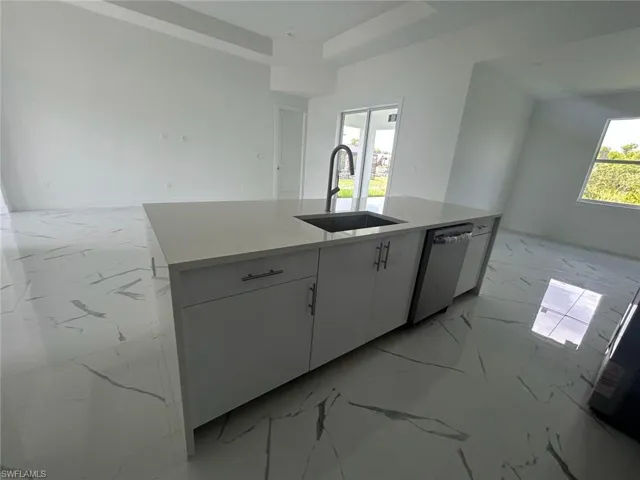 Kitchen with sink, dishwasher, a kitchen island with sink, and light tile floors