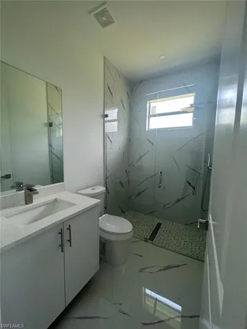 Bathroom with tile floors, an enclosed shower, oversized vanity, and toilet