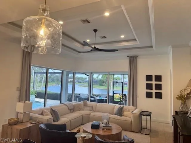 Living room featuring light tile patterned floors, ornamental molding, a raised ceiling, and a water view