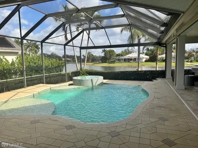 View of swimming pool with a patio, an in ground hot tub, a water view, and glass enclosure