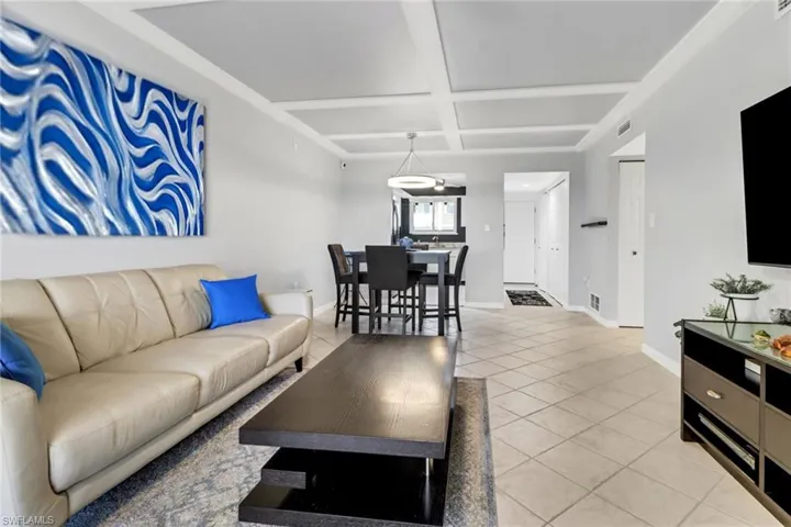 Living room with light tile patterned flooring and coffered ceiling