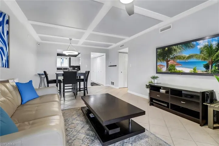 Tiled living room featuring ceiling fan and coffered ceiling