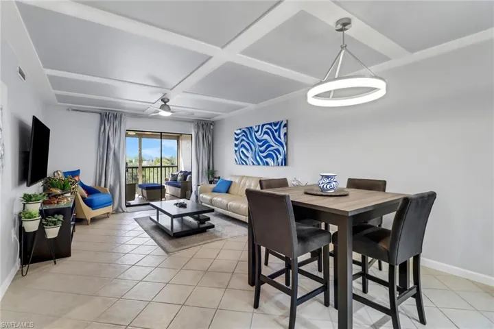 Dining room with light tile patterned floors, ceiling fan, and coffered ceiling