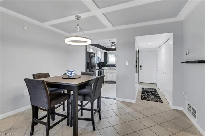Dining area featuring light tile patterned floors and coffered ceiling
