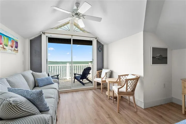 Living area with a water view, vaulted ceiling, light wood-style floors, and ceiling fan