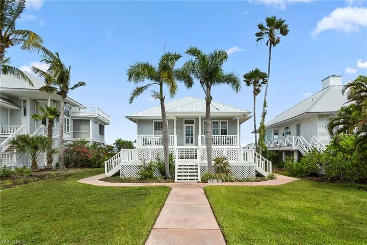 View of front of property with a front yard, stairway, a metal roof, and covered porch