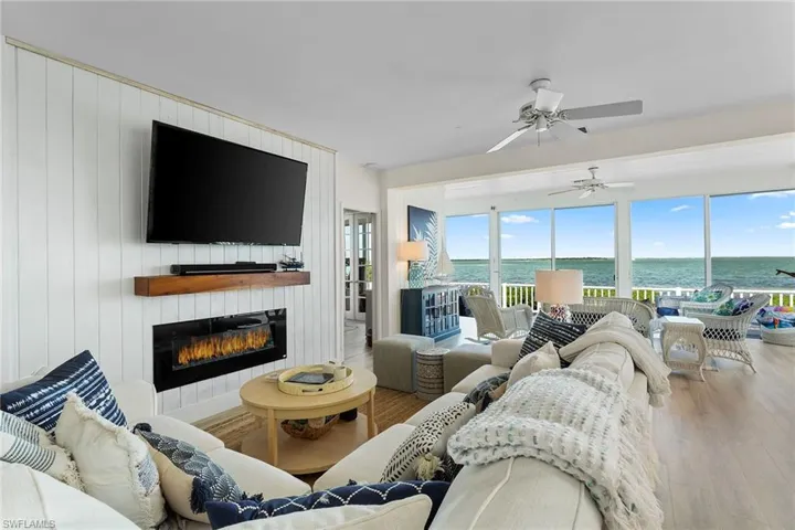 Living area featuring wood finished floors, a glass covered fireplace, and a ceiling fan
