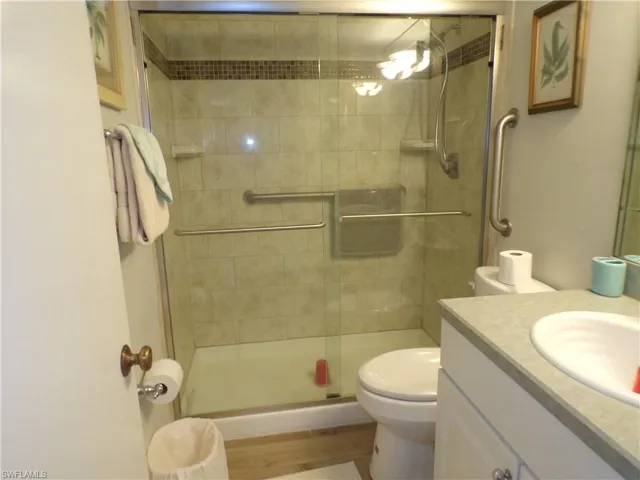 Bathroom with vanity, a shower stall, and light wood-type flooring