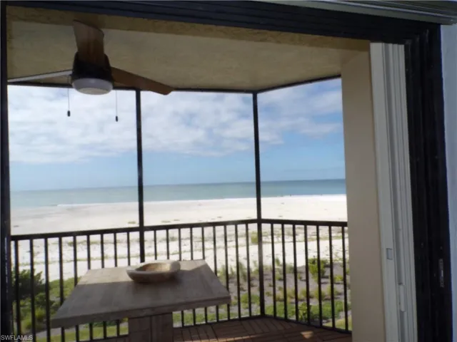 Balcony featuring a sunroom and view of water and beach
