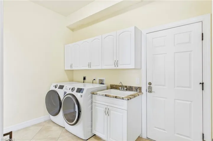 Spacious laundry room offers built-in cabinetry, utility sink & convenient functionality designed for everyday ease and organization.