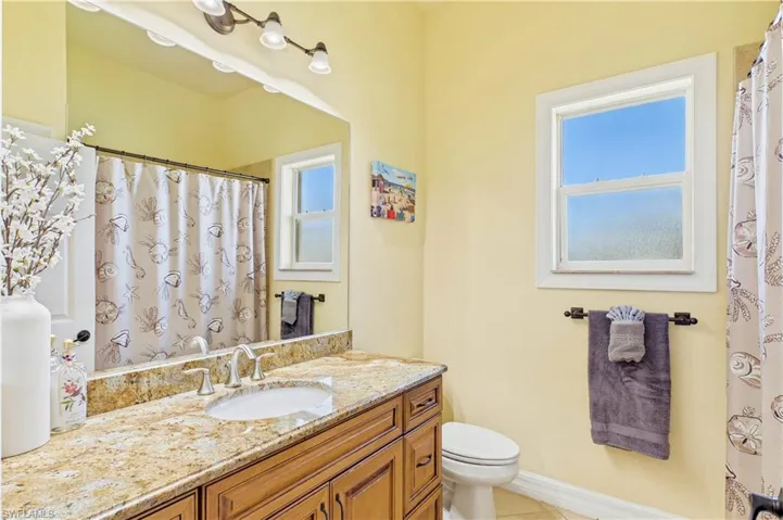 Hallway 3rd Bathroom - Well-appointed split guest bathroom features granite countertops, warm wood cabinetry & a bright coastal-inspired design ideal for family and visitors alike.
