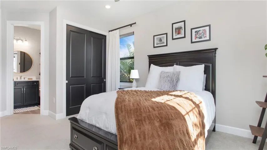 Bedroom featuring ensuite bath, sink, and light colored carpet
