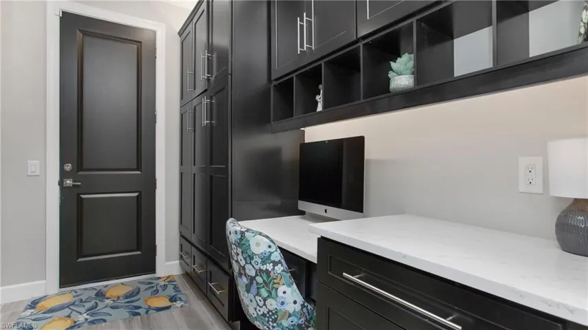 Home office with built in desk and light hardwood / wood-style flooring