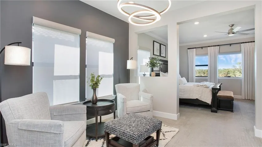 Carpeted bedroom with crown molding and ceiling fan with notable chandelier