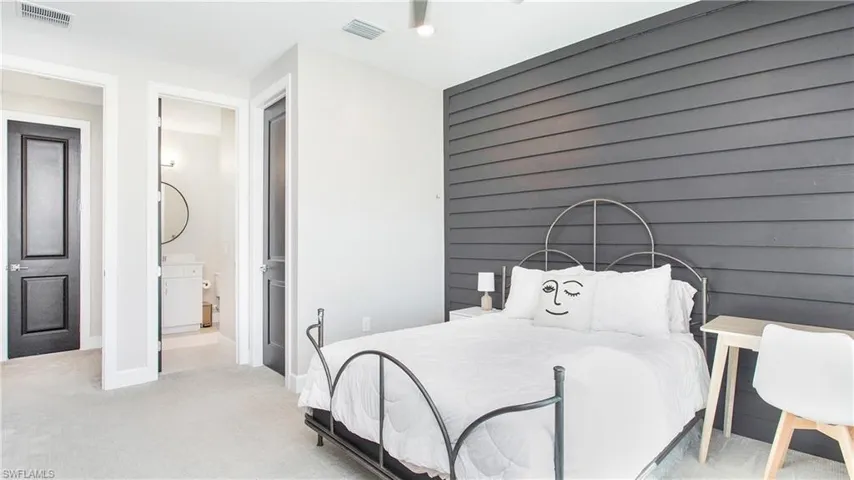 Bedroom featuring light colored carpet and connected bathroom