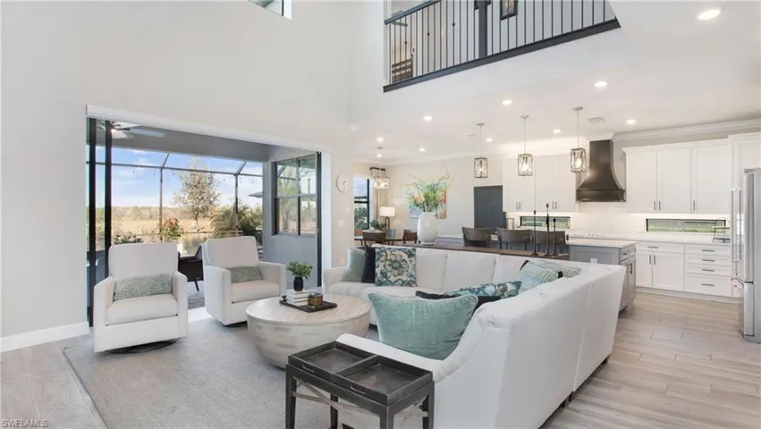 Living room featuring ceiling fan, light hardwood / wood-style flooring, crown molding, and a high ceiling