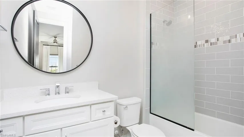 Full bathroom featuring ceiling fan, vanity, bath / shower combo with glass door, and toilet