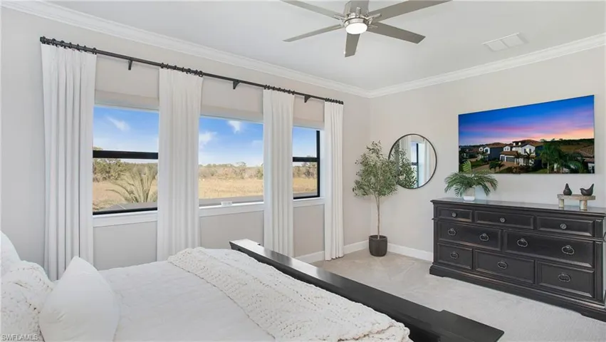 Bedroom with ceiling fan, light carpet, and ornamental molding