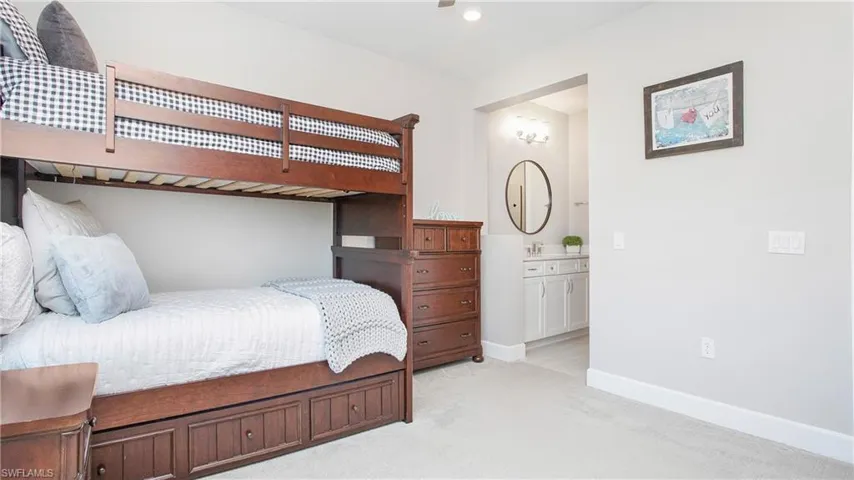 Bedroom featuring light colored carpet, ensuite bath, and sink