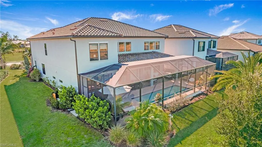 Rear view of house featuring glass enclosure and a lawn