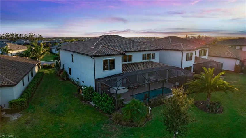 Back house at dusk with a lanai and a lawn