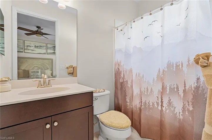 Bathroom with ceiling fan, vanity, and toilet