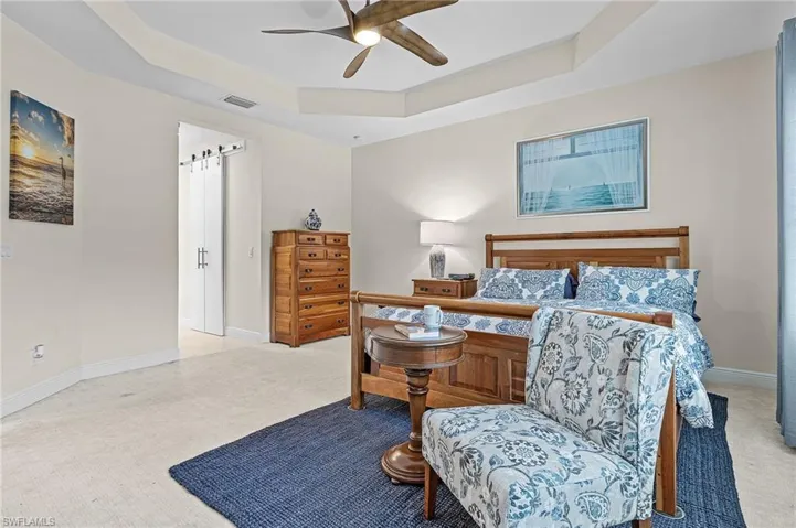 Carpeted bedroom with ceiling fan and a raised ceiling