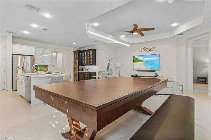 Tiled dining room featuring a tray ceiling, sink, and ceiling fan