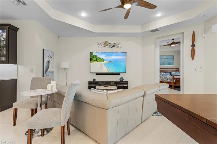 Living room with ceiling fan, a tray ceiling, and light tile floors