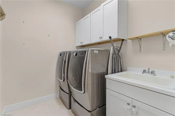 Washroom featuring independent washer and dryer, sink, cabinets, and light tile floors
