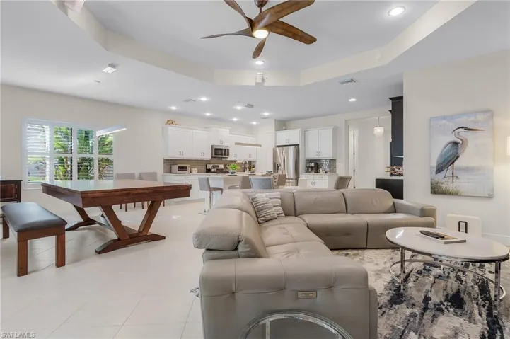 Tiled living room with sink, ceiling fan, and a raised ceiling
