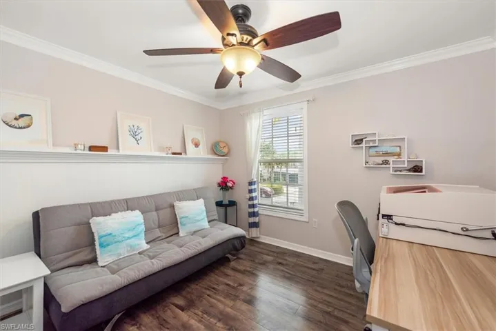 Home office with ornamental molding, dark wood-type flooring, and a ceiling fan