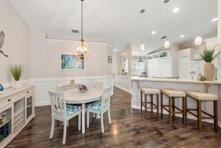 Dining room with recessed lighting, dark wood-type flooring, wainscoting, and a chandelier