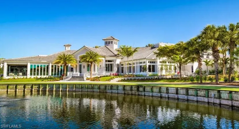 Back of house featuring a water view, a yard, and a tile roof
