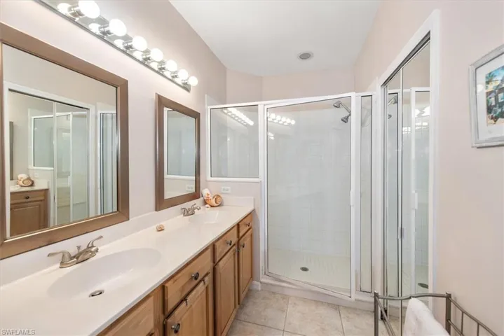 Full bathroom with double vanity, a shower stall, and light tile patterned floors
