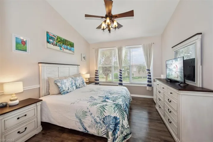 Bedroom with dark wood finished floors, lofted ceiling, and a ceiling fan