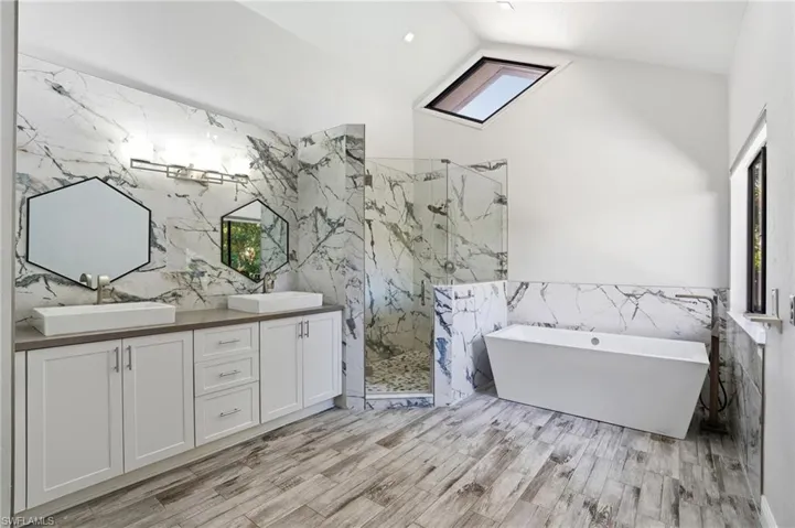 Spacious bathroom featuring a freestanding soaking tub, a frameless glass shower enclosure, and a double vanity with vessel sinks