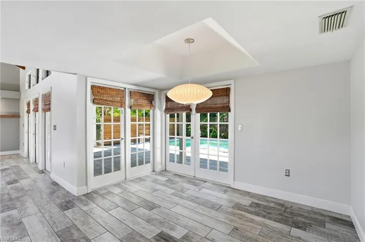 French doors with louvered blinds open to an outdoor pool area