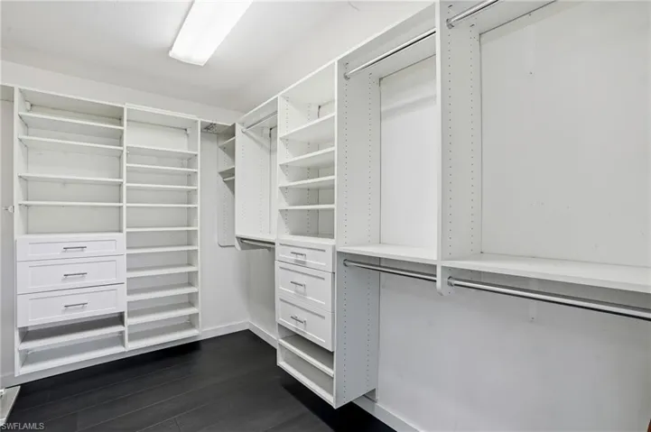 Custom closet system featuring multiple shelving units, built-in drawers with modern hardware, and chrome hanging rods