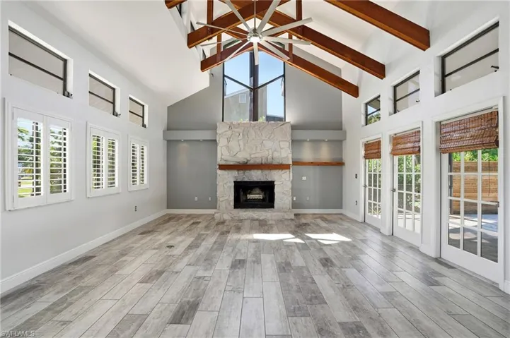 Vaulted ceiling great room featuring exposed wood beams and a stone-faced fireplace