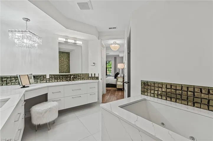 Ensuite bathroom with vanity, an inviting chandelier, decorative backsplash, visible vents, and ensuite bathroom