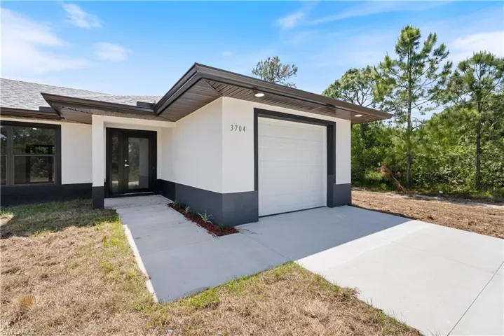 View of front of property featuring concrete driveway, roof with shingles, a garage, and stucco siding