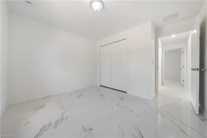 Unfurnished bedroom with a closet, marble finish floor, baseboards, and visible vents