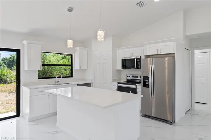 Kitchen featuring visible vents, marble finish floor, a sink, appliances with stainless steel finishes, and a kitchen island