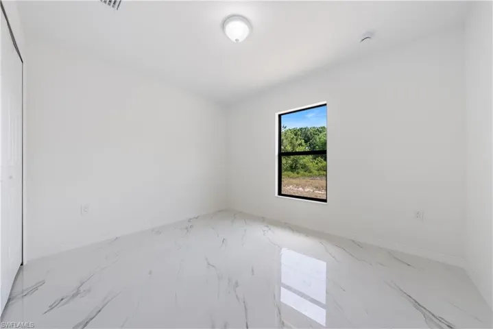 Spare room featuring marble finish floor and baseboards