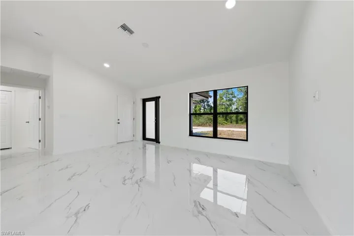 Spare room with visible vents, baseboards, recessed lighting, marble finish floor, and lofted ceiling