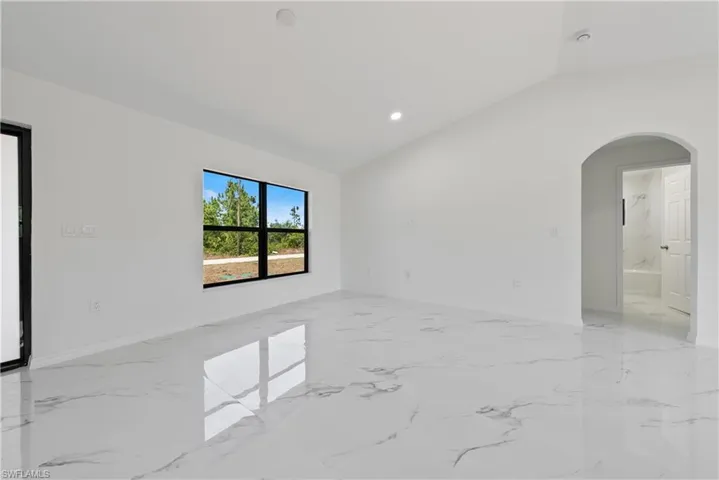 Spare room with baseboards, vaulted ceiling, recessed lighting, arched walkways, and marble finish floor