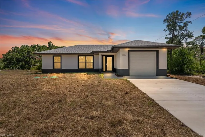Prairie-style house with a front yard, a garage, concrete driveway, stucco siding, and roof with shingles
